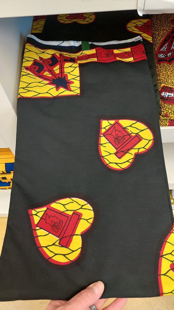 A black and yellow fabric with red and yellow designs.