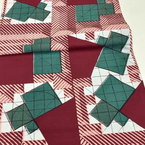 A red and green quilt with some white squares